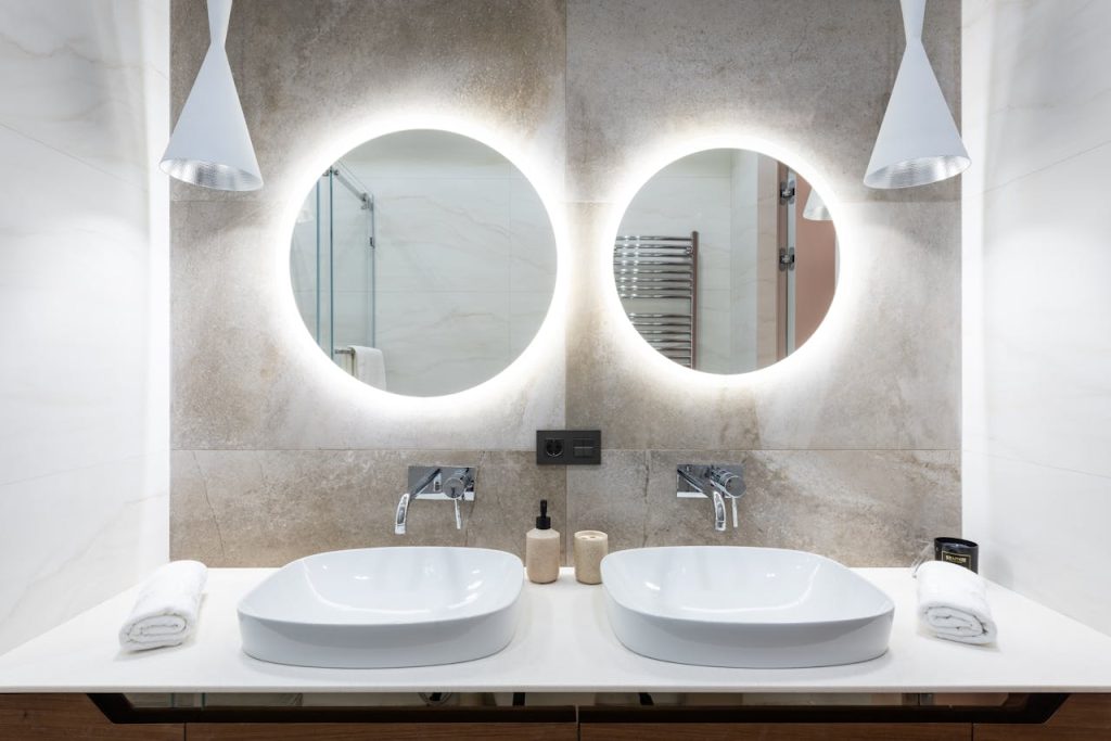 bathroom-interior-with-mirror-and-sink-6186825 Contemporary bathroom design featuring a stylish double vanity with round backlit mirrors.